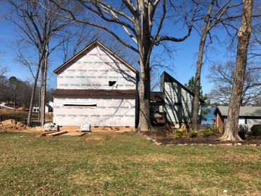 A house under construction with blue sky and leafless trees.
