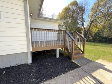 Small wooden deck with stairs leading to a backyard lawn.