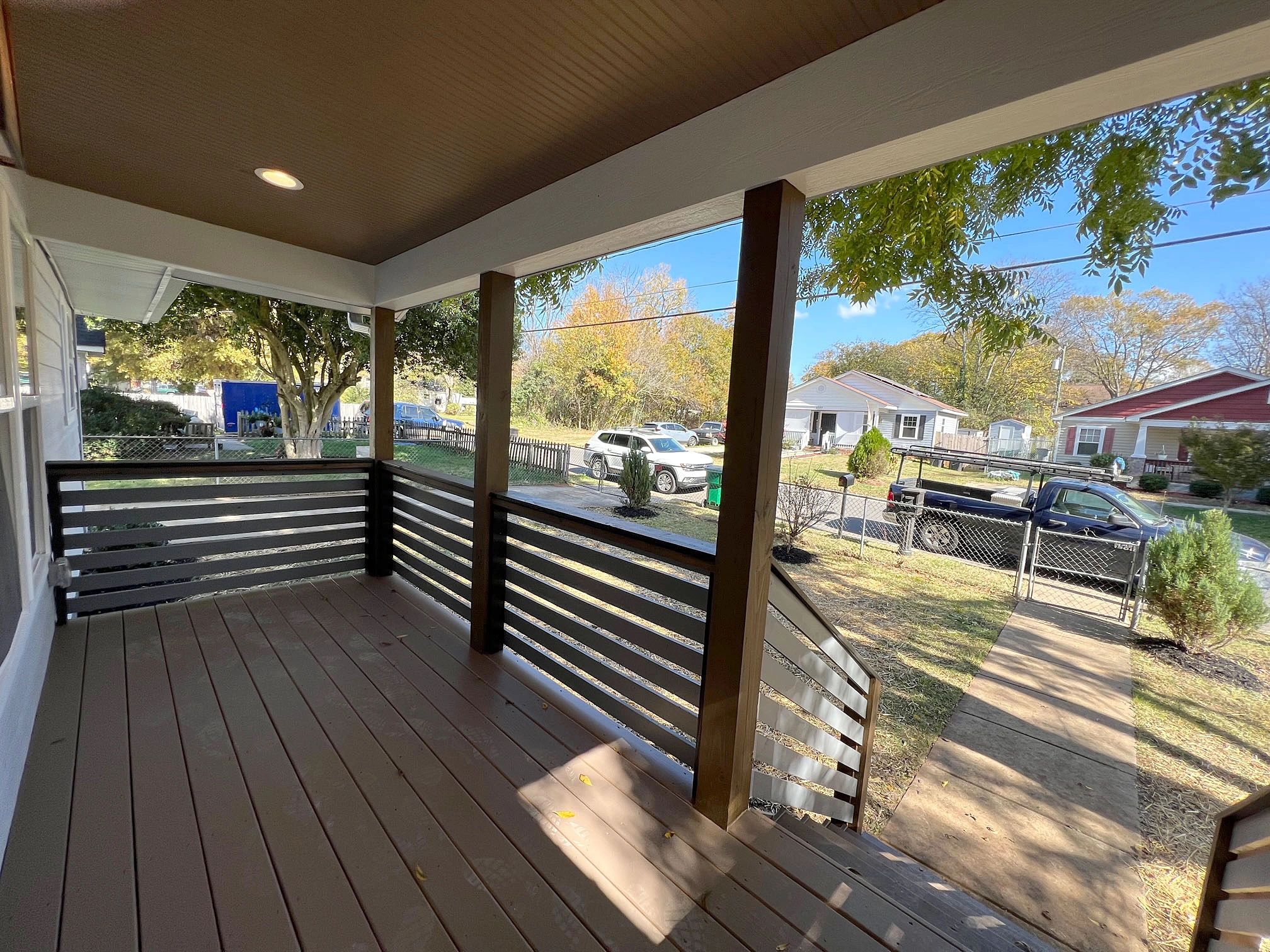 Empty front porch with wooden railings and a view of the neighborhood street.