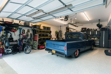 A blue vintage Ford pickup truck parked inside a well-organized garage.