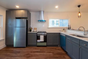 Modern kitchen with gray cabinets and stainless steel appliances.