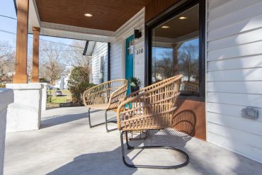 Cozy porch with wicker chairs and a bright blue door.