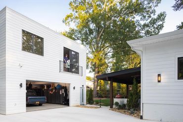 Modern white garage with an open door and a person on the balcony above.