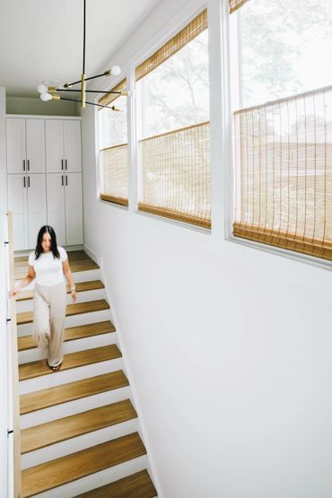Woman walking down wooden stairs in a bright, modern home.