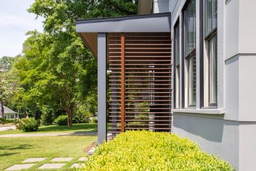 Modern house exterior with wooden slat design and lush greenery.