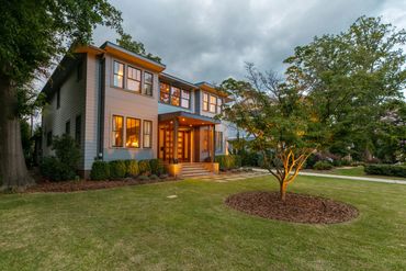 Modern two-story house with warm lights and well-kept lawn.