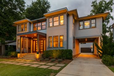 Modern two-story house with warm exterior lighting and a spacious driveway.