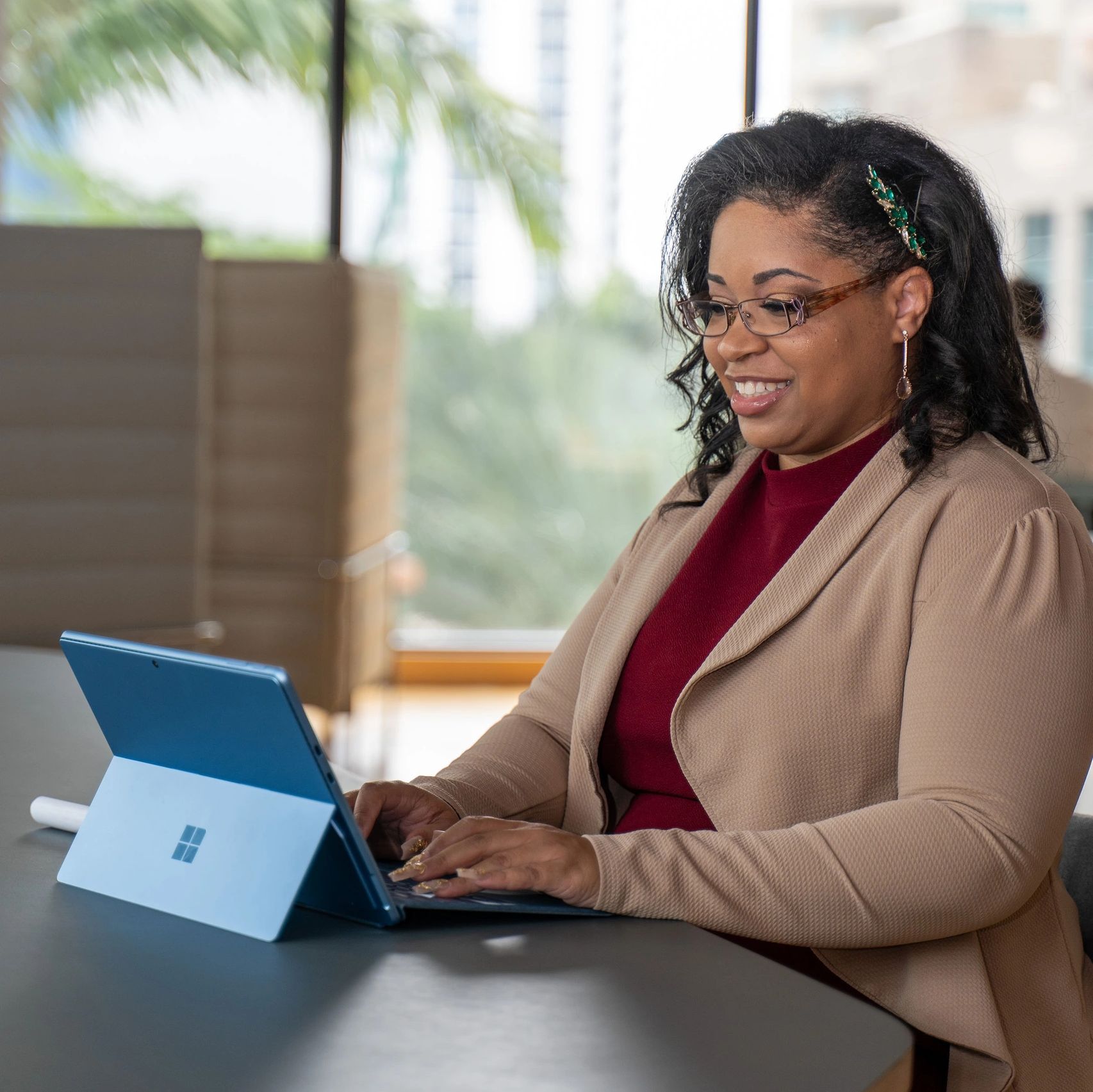 Image of woman dressed in business attire looking at computer screen and smiling.