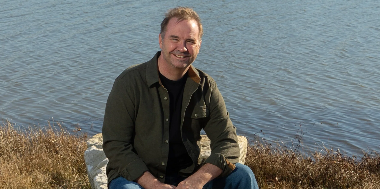 Greg Hall sits by his neighborhood lake, where he loves to fish and write.