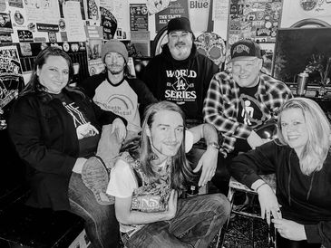 Group of six people posing indoors, black and white.