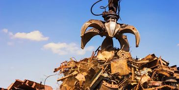 Industrial claw crane lifting scrap metal.
