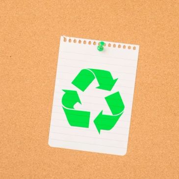 Green recycling symbol on a pinned lined paper.