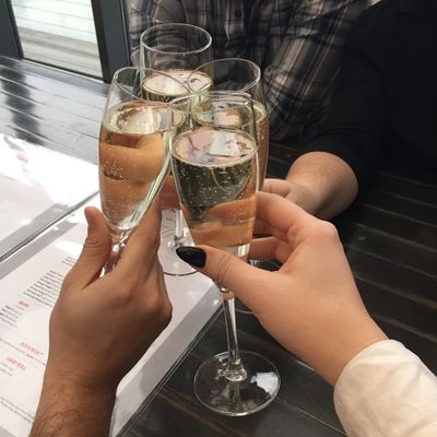 Four hands clinking champagne glasses in a celebratory toast.