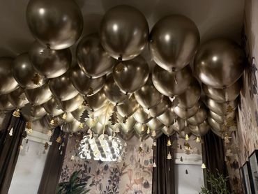 A ceiling densely covered with golden balloons and hanging decorations in a decorated room.