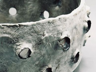 Close-up of a textured metal or ceramic object with holes.