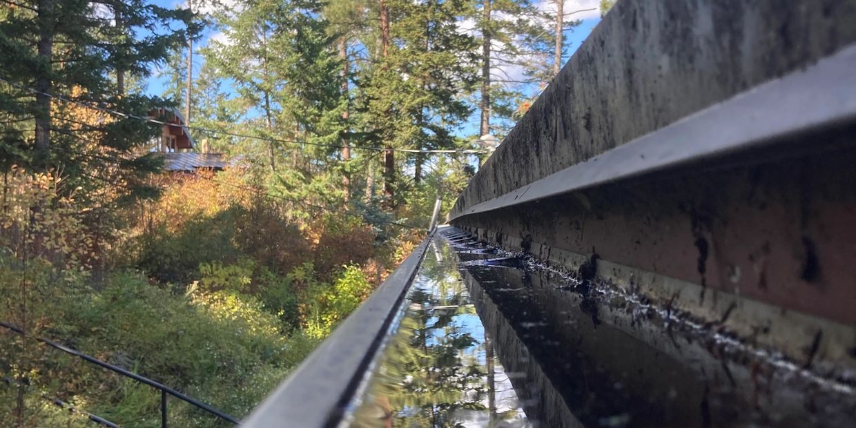 Water filled Lakeside rain gutter before a Flathead Valley Gutter Cleaners gutter cleaning service!