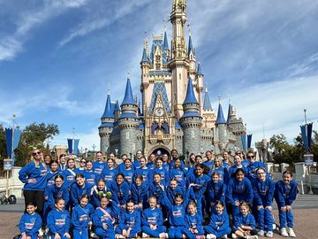 Group photo in front of a castle at a theme park.