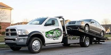 Tow truck carrying a silver sedan.