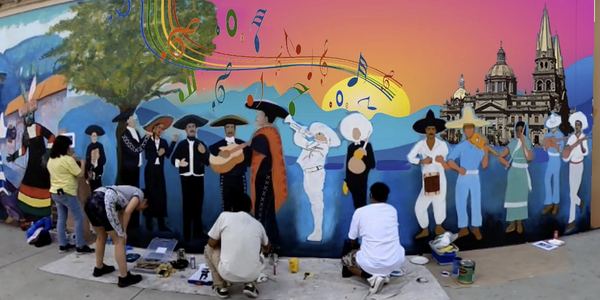 Artists painting a vibrant mural of Mexican culture and music on a city wall.