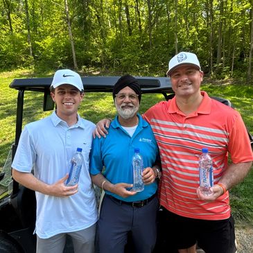 Three men posing with water bottles in front of a golf cart on a sunny day.