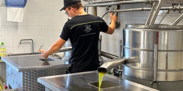 A man operating industrial stainless steel equipment with green liquid flowing.