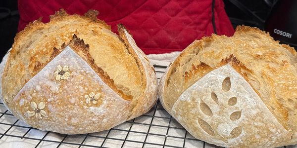 Two beautifully baked sourdough loaves with decorative scoring and toppings.