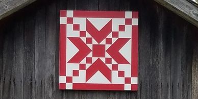 This is a lovely 2'x 2' traditional pattern red and white quilt displayed on a weathered coup