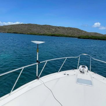 View from a boat bow looking toward a calm island shore.