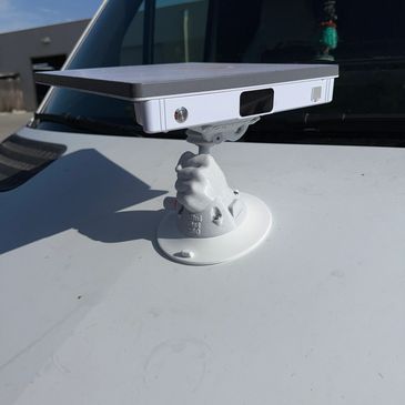 Unique phone holder mount with a hand-shaped base on a car hood.