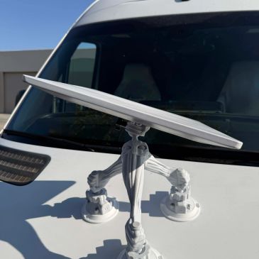 Solar panel mounted on a white vehicle hood with suction cups.