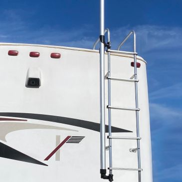 Ladder attached to the back of a white RV under a clear blue sky.