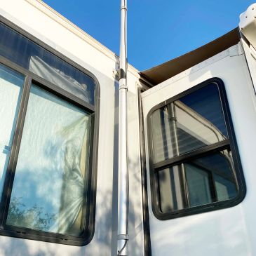 Close-up of two RV windows under clear blue sky.