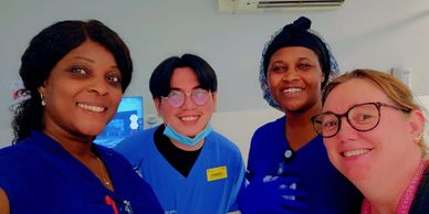 Four diverse healthcare workers smiling together in a clinical setting.