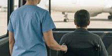 Caregiver assisting a person in a wheelchair at an airport.