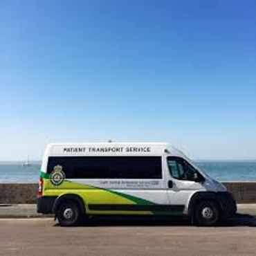 Patient Transport Service van parked near the seaside under a clear blue sky.