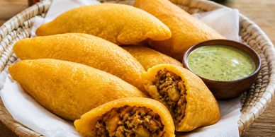 Golden fried empanadas with a spicy filling and green dipping sauce.