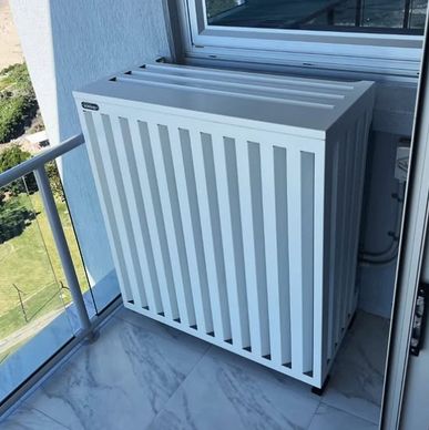 White radiator cover on a balcony with a view of greenery.