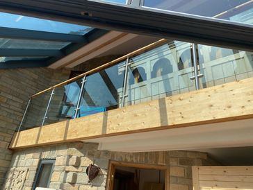 Modern balcony with glass railing and wood accents.