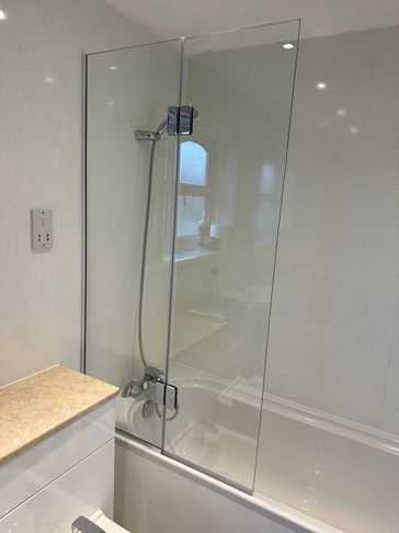 Modern bathroom with bathtub and glass shower screen.