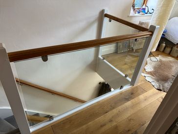Modern glass and wooden stair railing in a home.