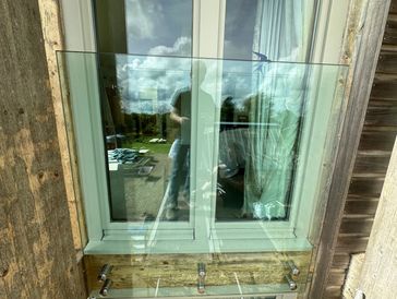 Glass window with reflection of a person and outdoor scenery.