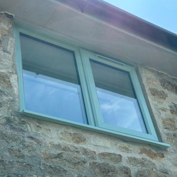Modern green window on stone wall.