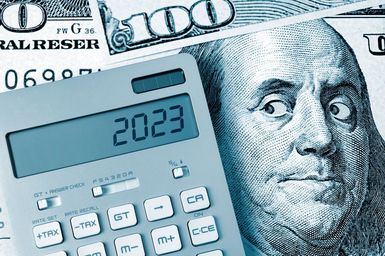 Benjamin Franklin on a 100 dollar bill looking at a calculator with the date 2023