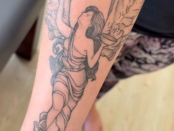 A tattoo design of an angel created by Meme Rese of on a forearm 