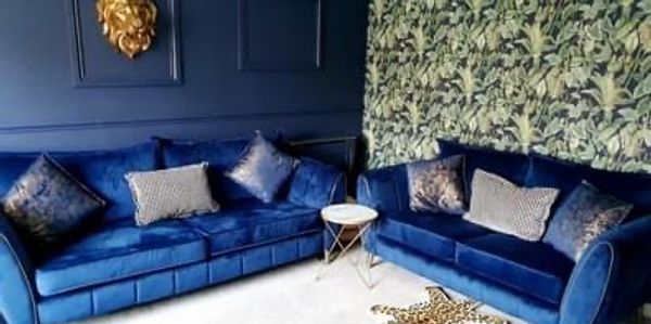 Two blue velvet sofas in a stylish living room with a lion head wall decor. Wallpaper and blue painted walls 