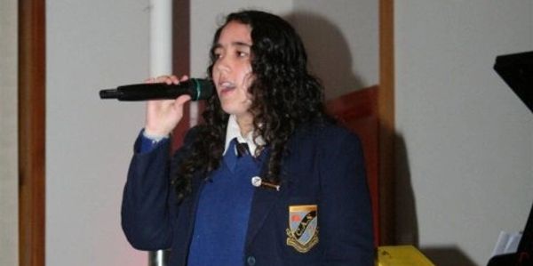 Sofia singing with mic in school uniform