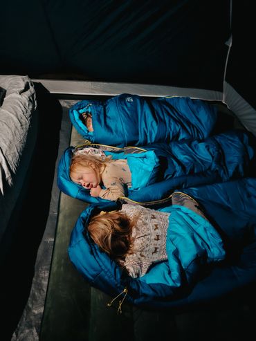 Adalaide, Wilder, and Noah sleeping in their sleeping bags on an air mattress in the tent.