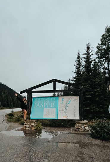 Sarah standing on the welcome to Jasper sign. 