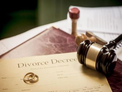 Divorce decree with wedding rings and a judge's gavel.