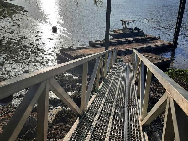 Metal ramp leading to a small dock and boat on water.